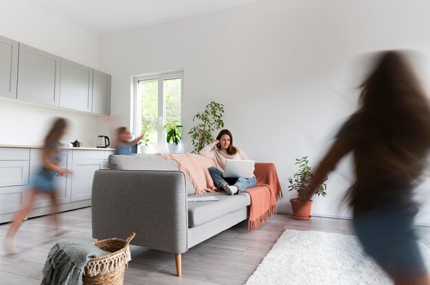 Woman trying to work on laptop from home while her children are running around