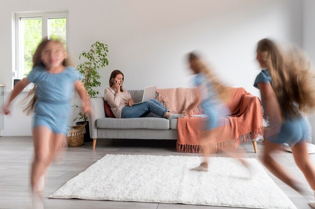 Woman trying to work on laptop from home while her children are running around