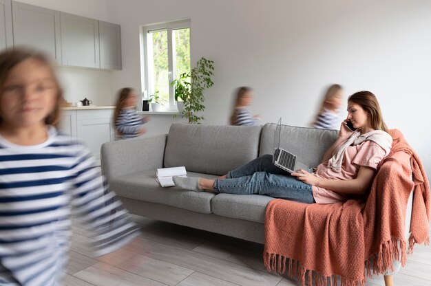 Woman trying to work on laptop from home while her children are running around