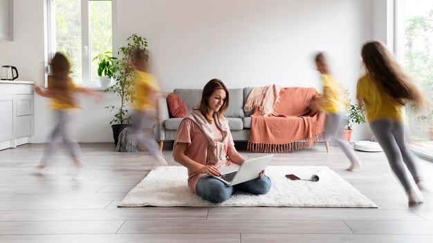 Woman trying to work on laptop from home while her children are running around