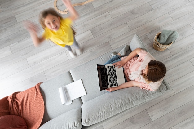 Woman trying to work on laptop from home while her children are running around