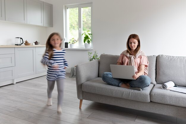 Woman trying to work on laptop from home while her children are running around