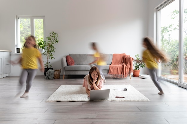 Woman trying to work on laptop from home while her children are running around