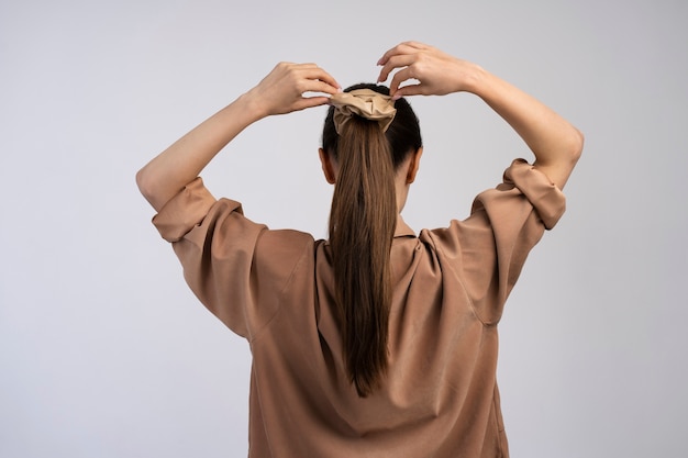 Женщина завязывает волосы, вид сзади