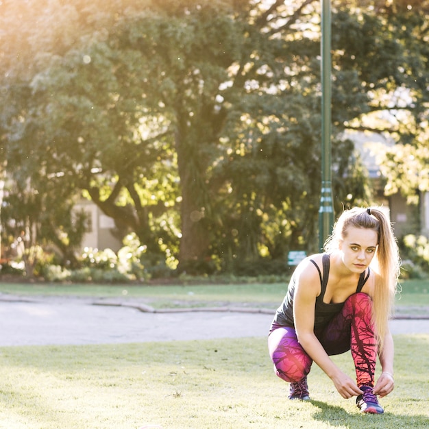 Free photo woman tying laces and looking at camera