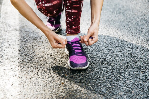 Woman tying running shoes on road
