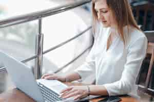 Free photo woman typing on a laptop in a coffee shop