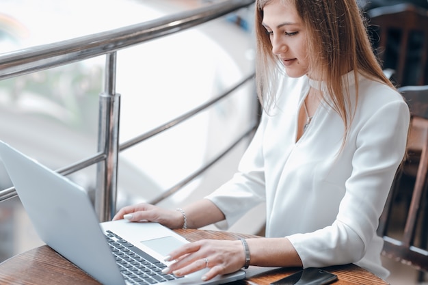 Woman typing on a laptop in a coffee shop