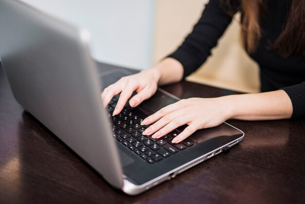 Женщина печатает на клавиатуре ноутбука