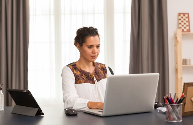 Женщина печатает на ноутбуке во время работы из домашнего офиса.