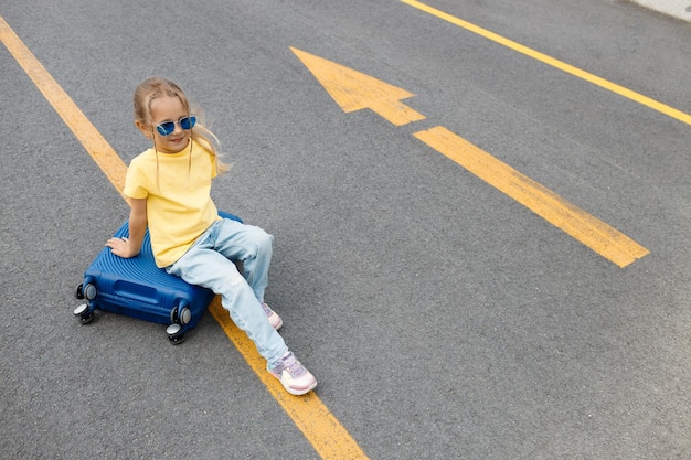 スーツケースと道路上のウクライナの旗の色の女性