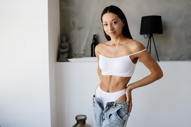 Woman undressing jeans, white underwear. Young woman is taking her jeans off. Woman look sensuality and sexy.