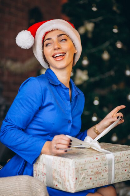 クリスマスツリーでプレゼントを開梱する女性
