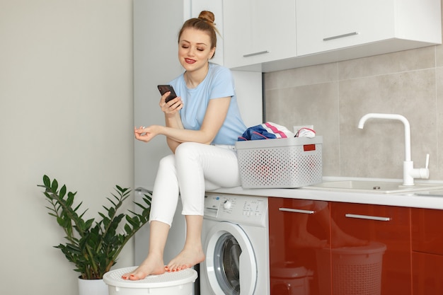 Woman uses a washing machine in the kitchen