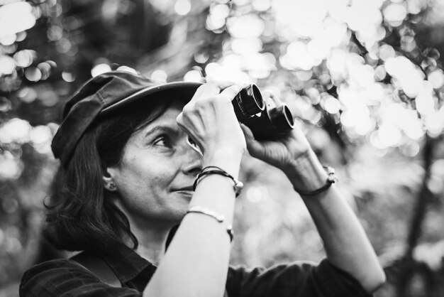 Woman using binoculars in the forest