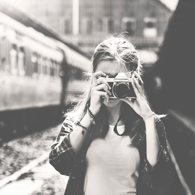 Free photo woman using camera taking photo at train station grayscale