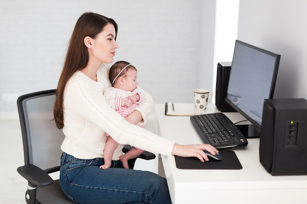 Woman using computer and holding daughter