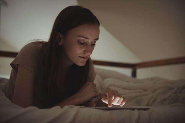 ベッドでデジタルタブレットを使用している女性