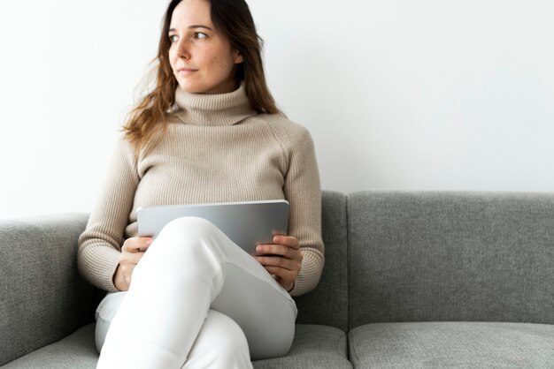 Женщина с помощью цифрового планшета на диване