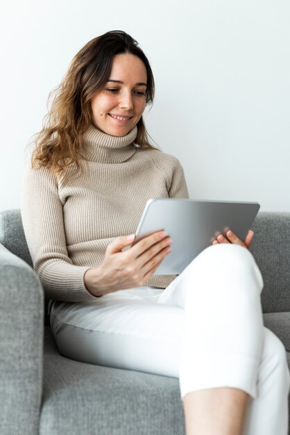 ソファでデジタルタブレットを使用している女性