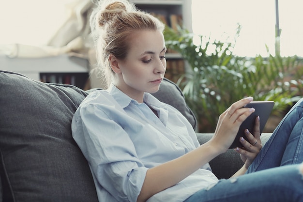 Foto gratuita donna che per mezzo della compressa o dello smartphone digitale