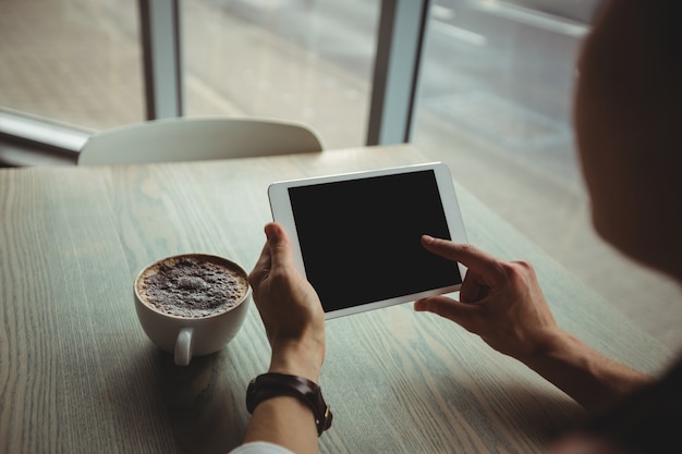 Woman using digital tablet while having cup of coffee