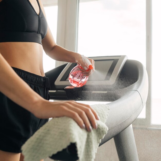 Woman using disinfectant on gym equipment