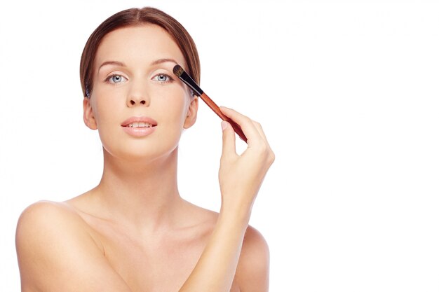 Woman using eyeshadow on eyelid