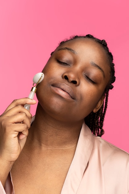 Woman using face roller medium shot