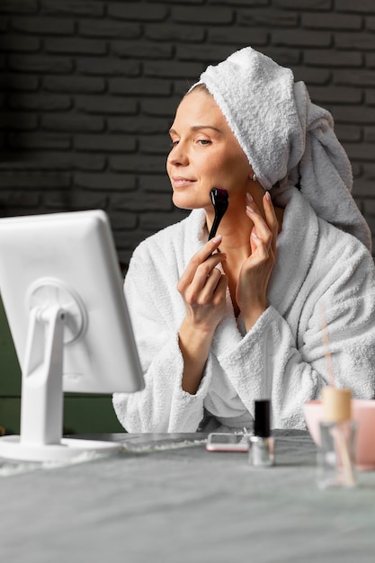 Woman using facial tool medium shot