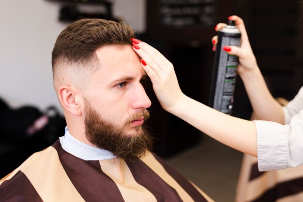 彼女のクライアントにヘアスプレーを使用して女性