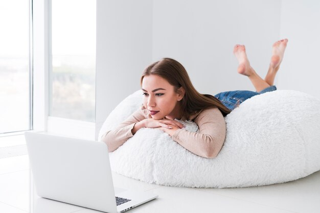 Woman using her laptop and sitting on a bean bag