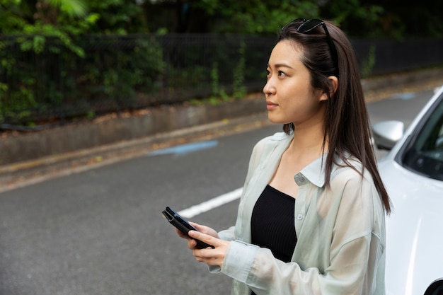 電気自動車の充電中にスマートフォンを使用している女性