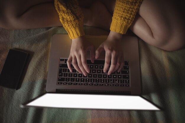 Woman using laptop on bed