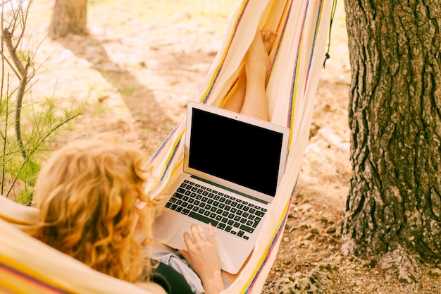 Woman using laptop in hammock