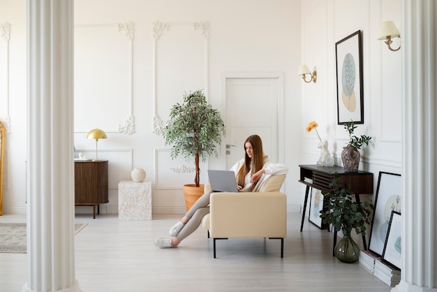 Бесплатное фото Женщина с ноутбуком в минималистично оформленной комнате