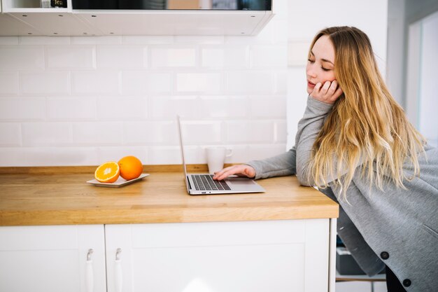 Foto gratuita donna che utilizza computer portatile sulla cucina