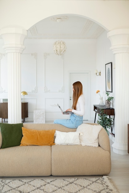 最小限の装飾が施された部屋でラップトップを使用している女性