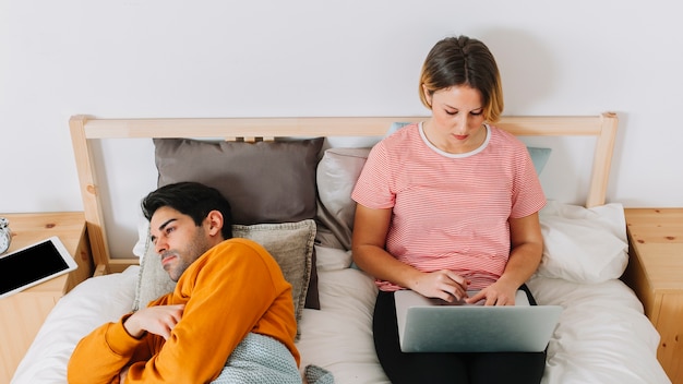 Woman using laptop near sad man