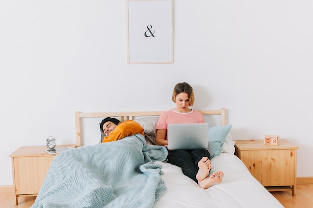 Woman using laptop near sleeping man