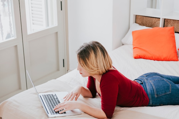 Бесплатное фото Женщина, используя ноутбук на кровати