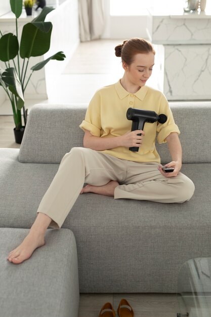 Woman using massage gun for arm full shot