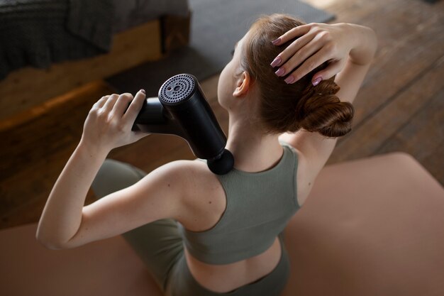 Woman using massage gun high angle