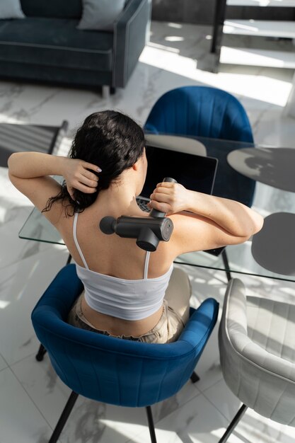 Woman using massage gun high angle