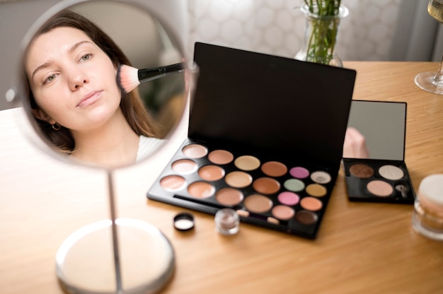 Free photo woman using mirror for make up