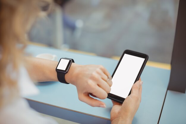 Woman using mobile and checking time at counter