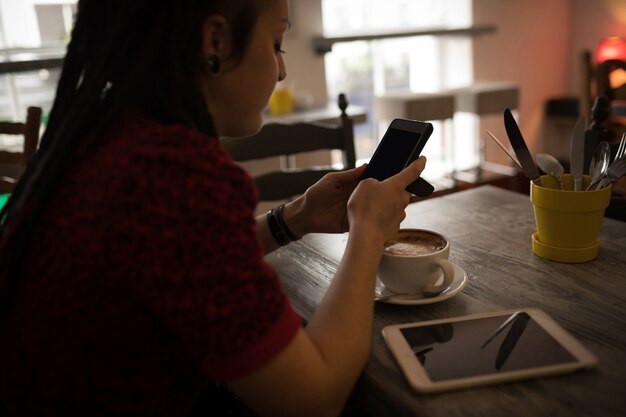 カフェで携帯電話を使用している女性