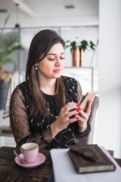 Foto gratuita donna che utilizza telefono cellulare nella caffetteria