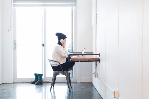 Woman using phone and laptop in office