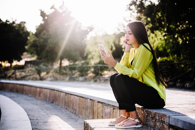 Женщина, используя телефон в солнечном парке